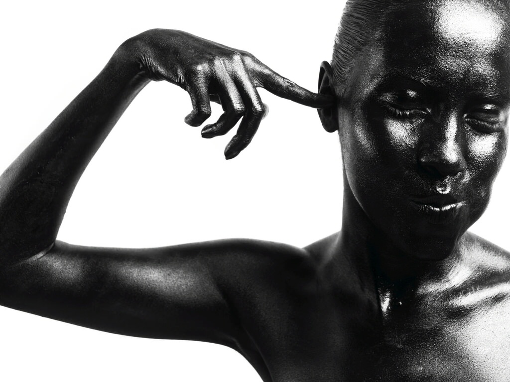 Black woman pointing at here ear. Studio photography.