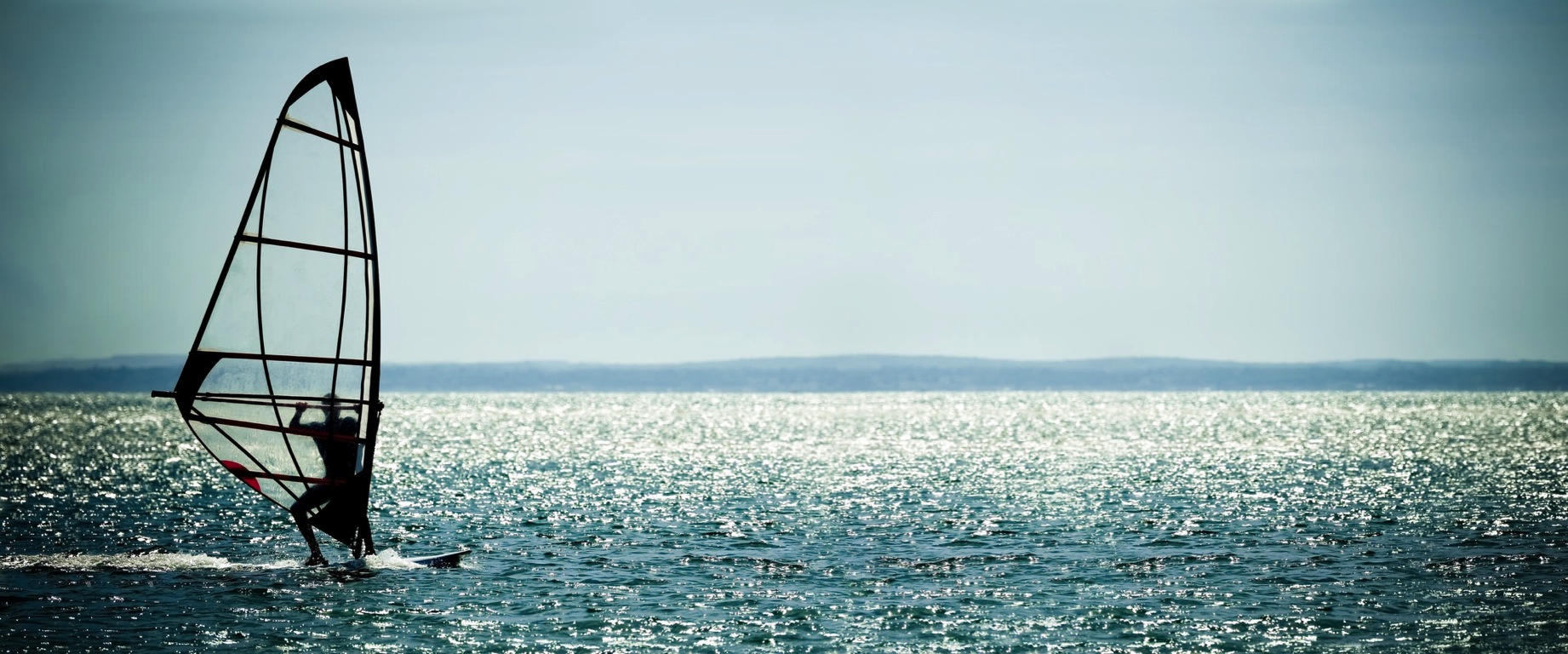 Windsurfer panorama silhouette against a sparking blue sea